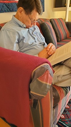 man snoozing on couch with book